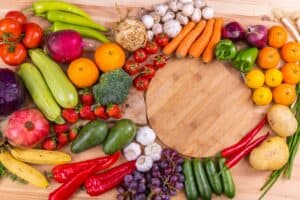 An array of brightly-colored eye-healthy vegetables, such as citrus and carrots, laying on a wooden counter.