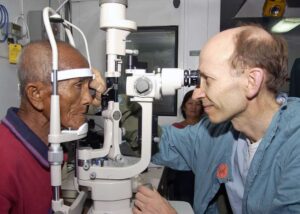 Doctor conducting eye exam on elderly male patient. 