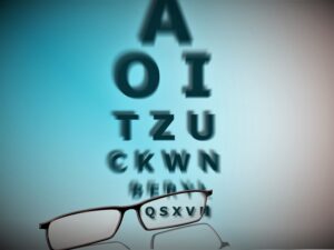 A pair of glasses looking at the bottom row of a snellen chart through one lens.