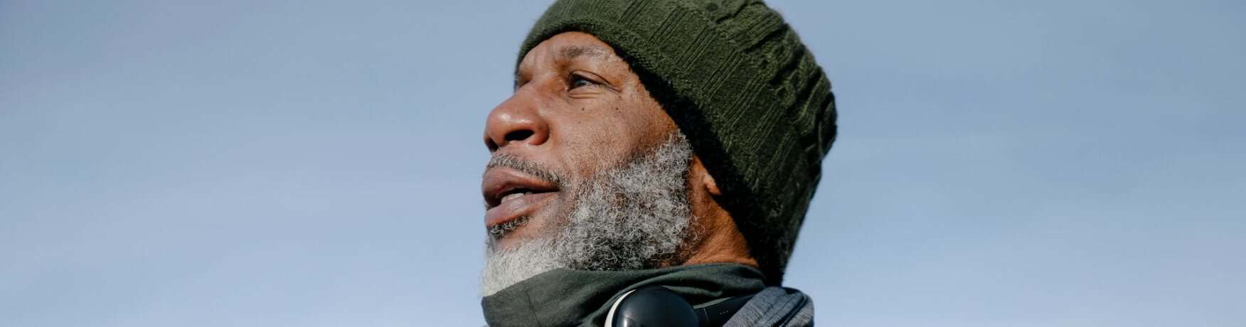 A man in a beanie and running top out walking outdoors on a cold morning.